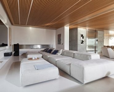 Family room with white walls and TV on wall together with a long sofa. Photo Credit: RuiTeixeira