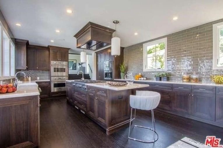 This classy U-shaped kitchen features a hardwood flooring matching the finish of the cabinetry, counters and the center island. The recessed lights brighten up the whole kitchen area.