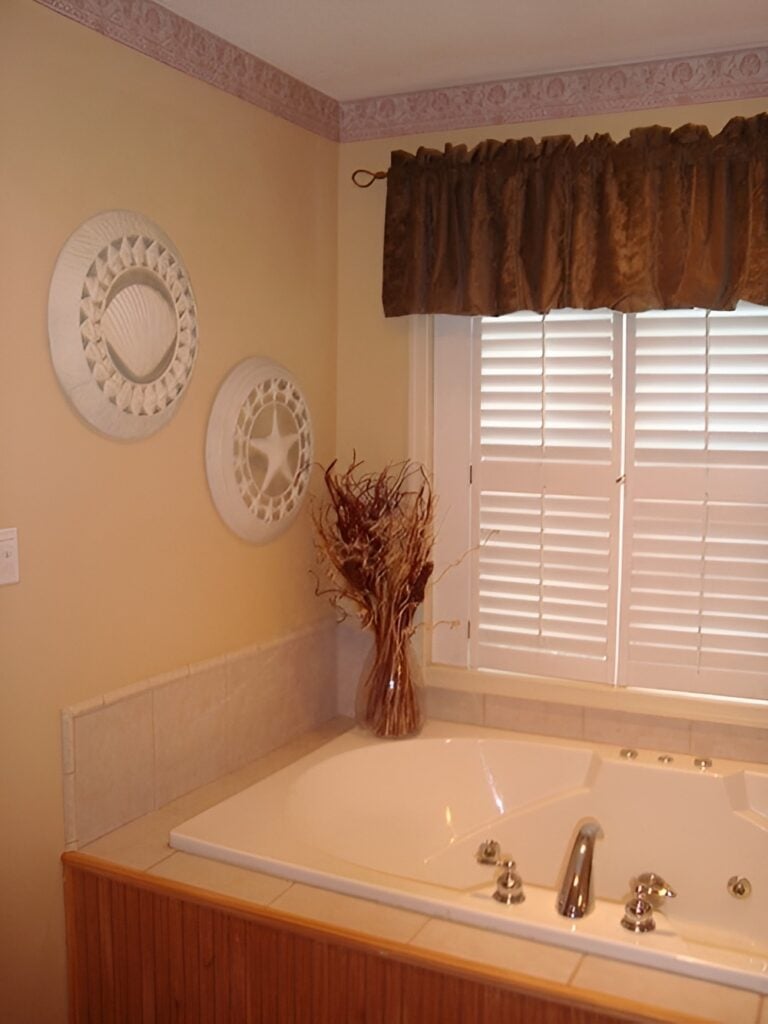 The primary bathroom features a drop-in bathtub fixed under the louvered window.