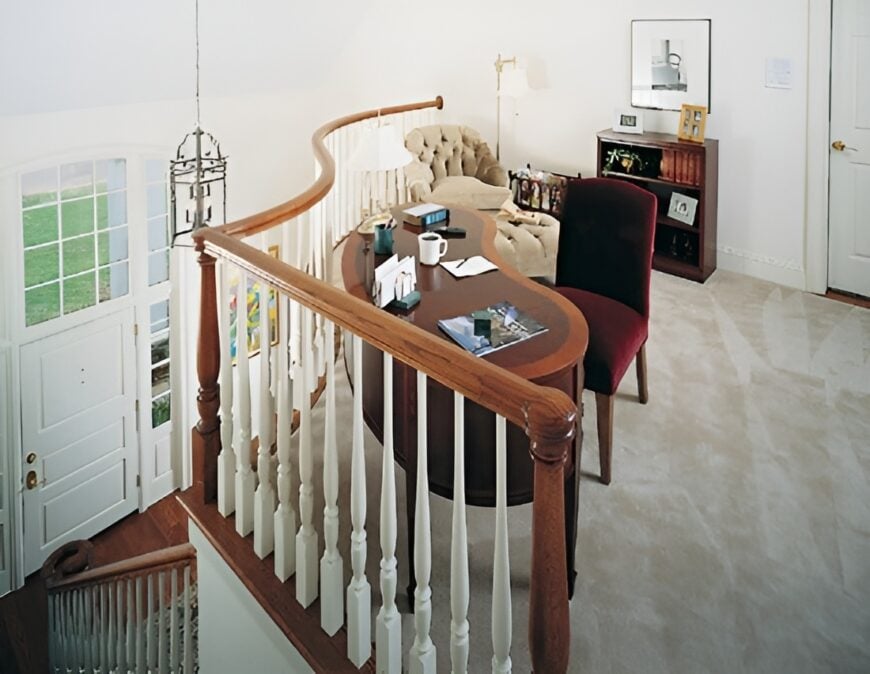 Balcony loft with velvet seats and a wooden desk over carpet flooring.