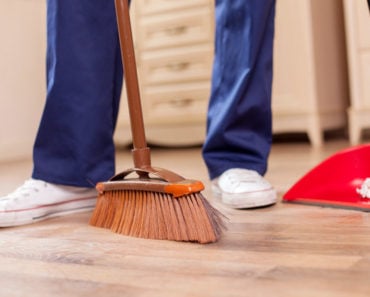 Man sweeping the floor with broom and upright dust pan