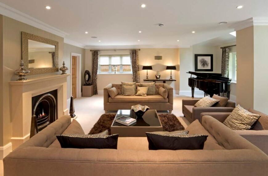 Lounge-like living room with brown sectional sofa, fireplace, recessed lighting and black grand piano.