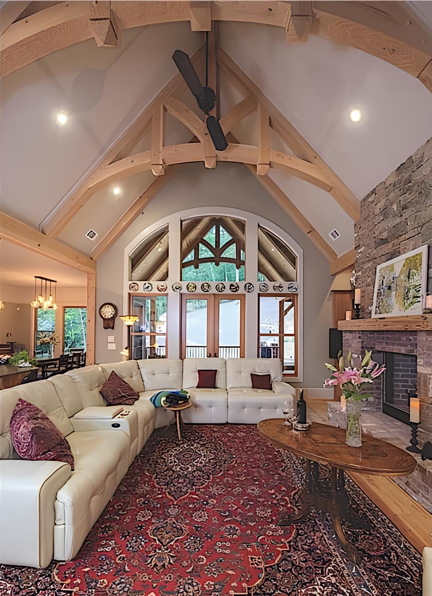 Great room with a leather tufted sectional, a stone fireplace, and a cathedral ceiling graced with exposed trusses.