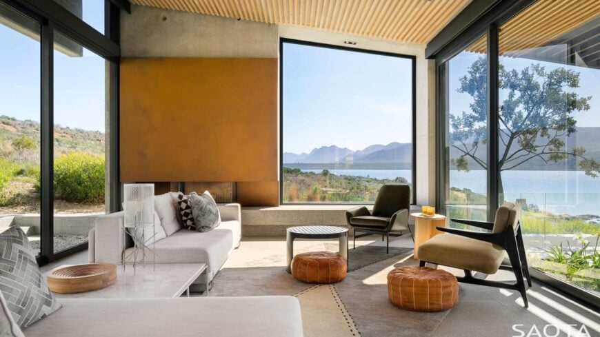 A modern formal living room featuring a nice set of seats and glass windows overlooking the beautiful surrounding.