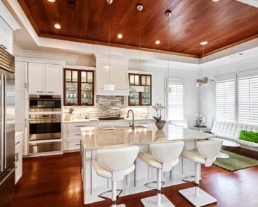 Kitchen with incredible wood ceiling and recessed light creating a more natural appearance in an otherwise all white kitchen design.