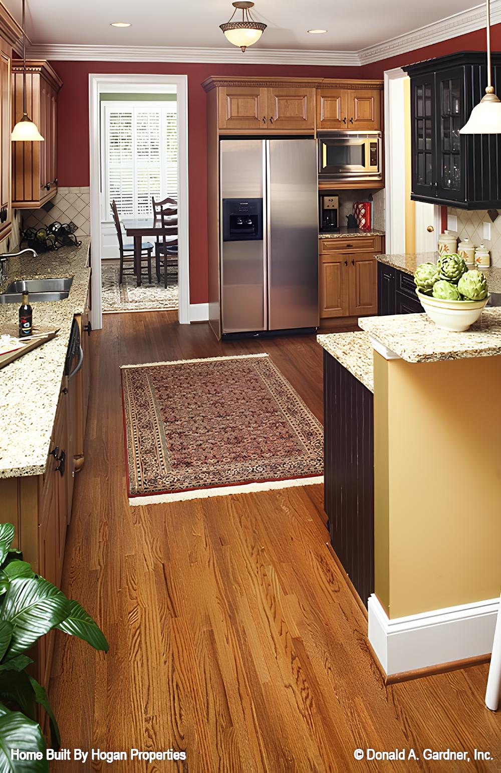 The kitchen includes stainless steel appliances and a tasseled rug that lays on the hardwood flooring.