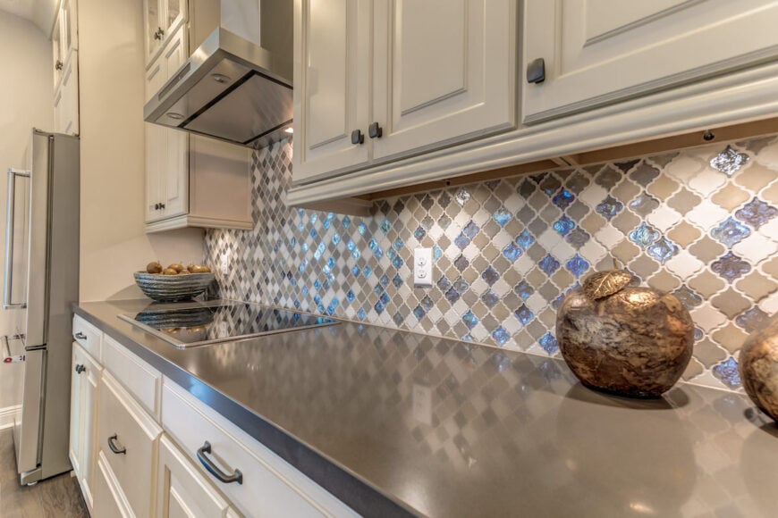 Zellige, In the Right Order — Modern kitchen with white cabinetry, grey quartz countertop, and patterned blue zellige backsplash.