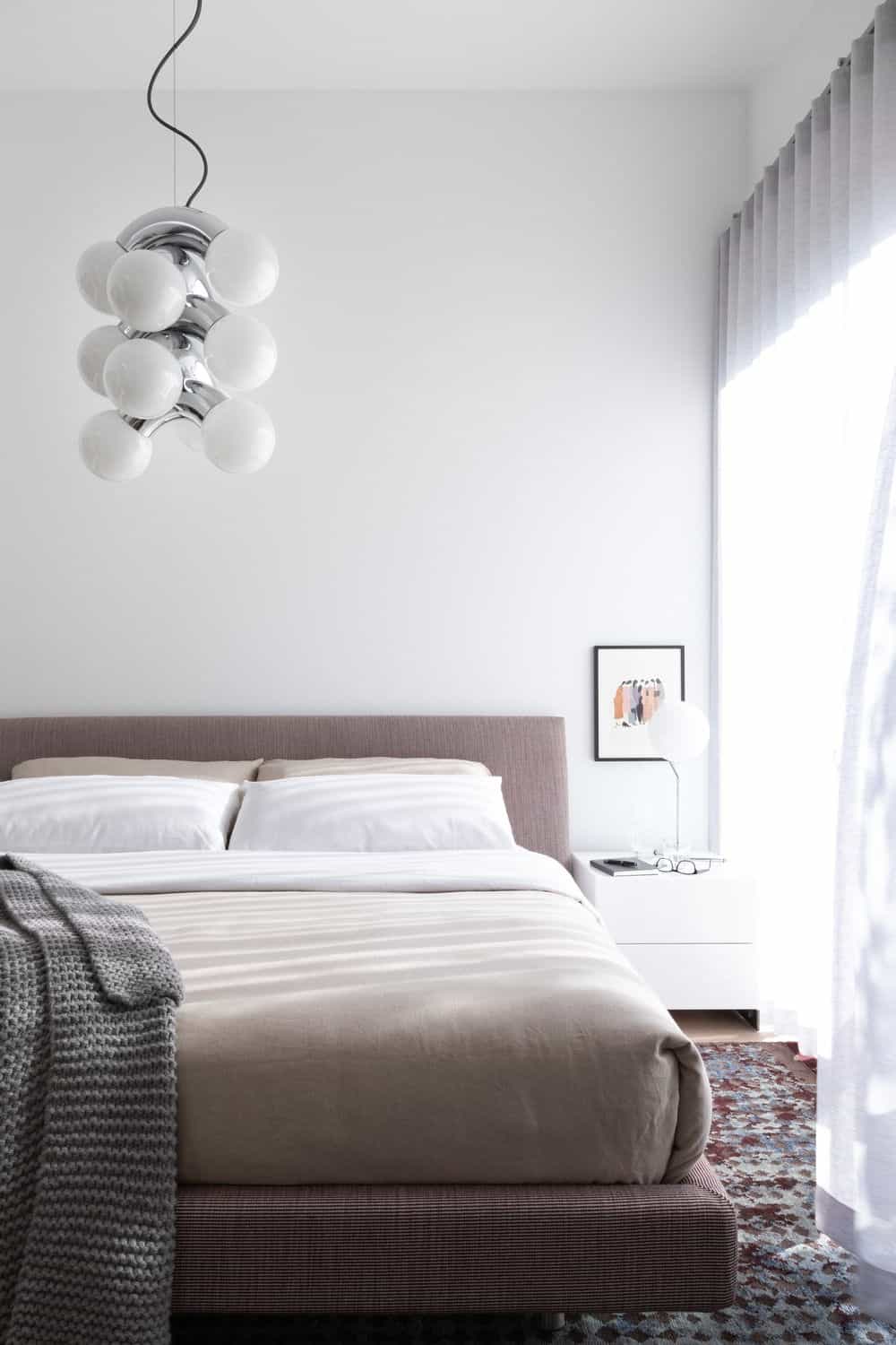 Another bedroom features a queen size bed lighted by a stylish ceiling light. Photo credit: Ema Peter