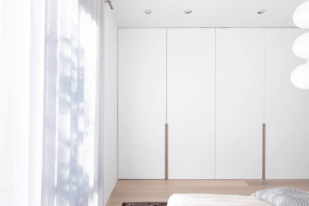 Another view of the bedroom focusing on its white walls and beautiful curtains. Photo credit: Ema Peter