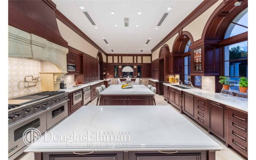 A huge kitchen area featuring a dining nook, a breakfast bar and a preparation center island. The brown shade of this kitchen adds class to the space.