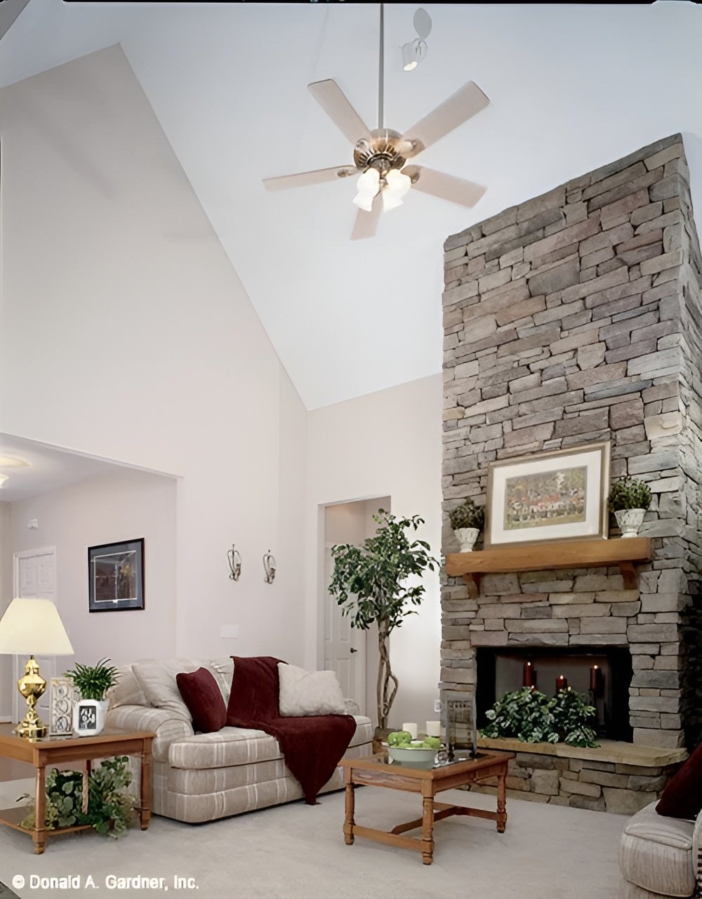 The great room offers striped sofas, wooden tables, and a stone fireplace.