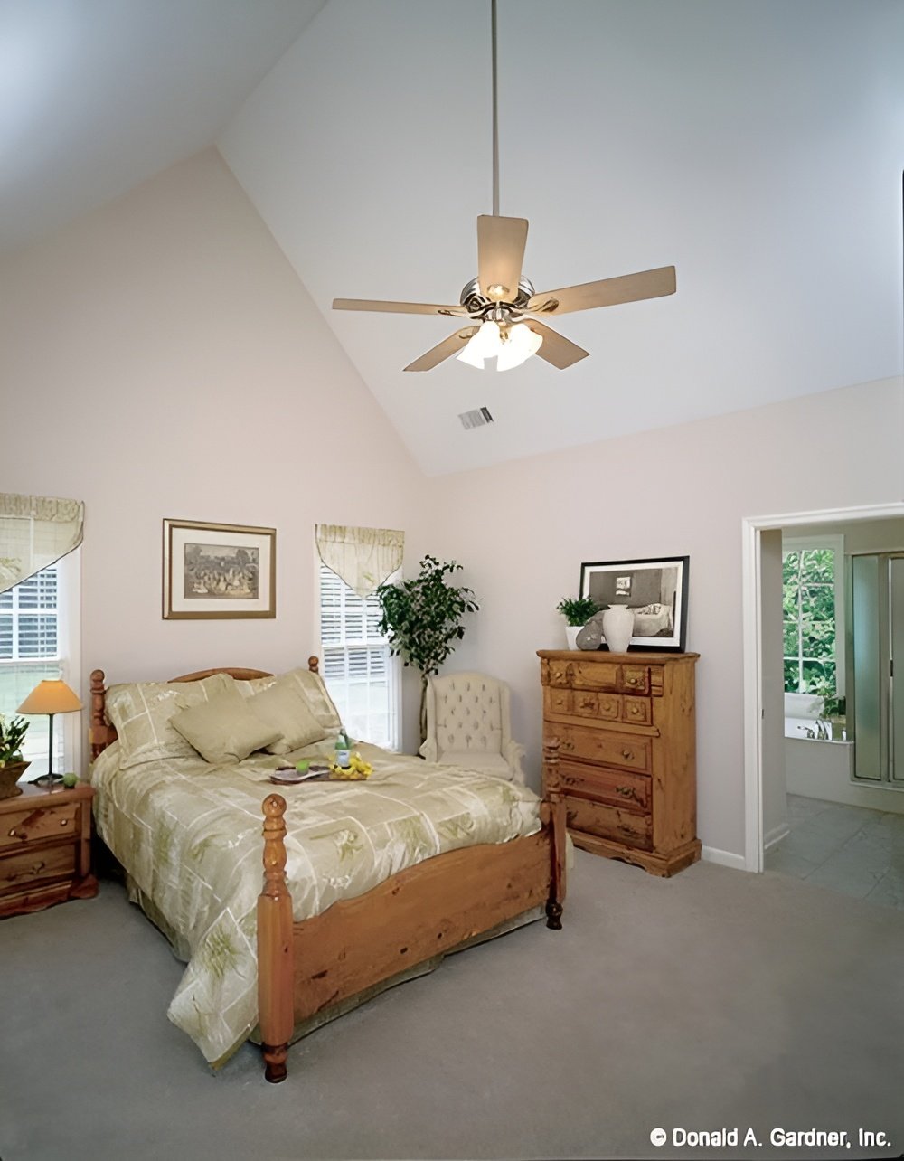 The primary bedroom features a cathedral ceiling and wooden furnishings over carpet flooring.