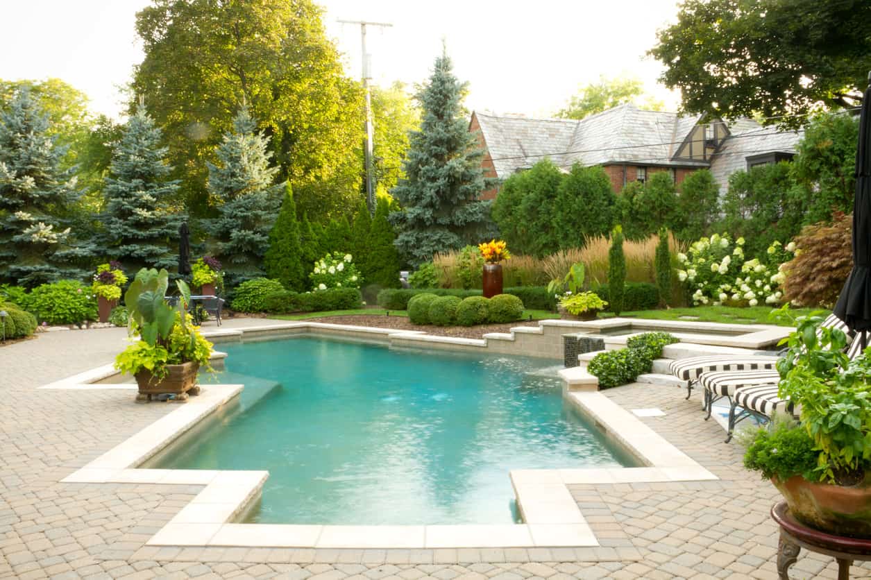 Here's an example of how surrounding flowers and bushes can enhance the look of an already beautiful pool. I love the brick patio with off-white pool border.
