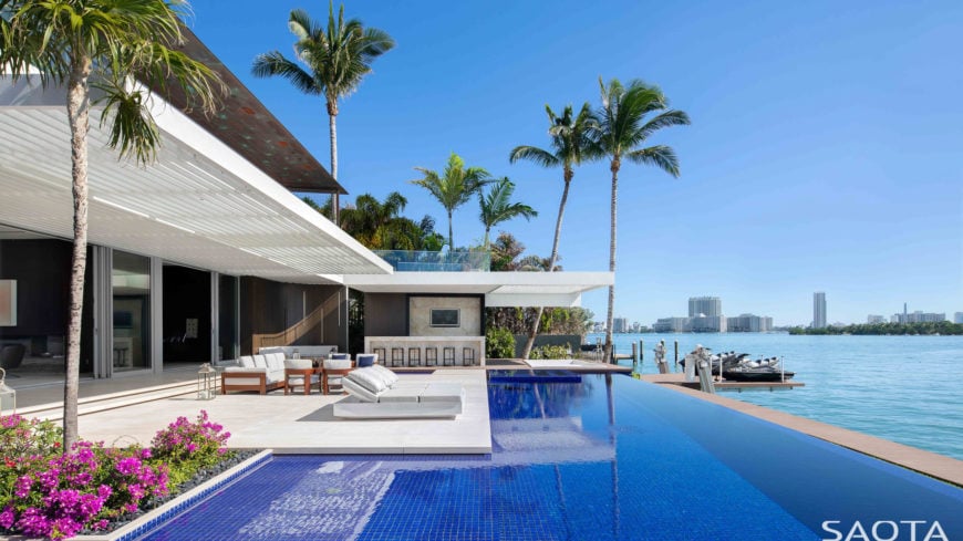 Stunning infinity pool featuring a set of loungers and a patio area on the side.