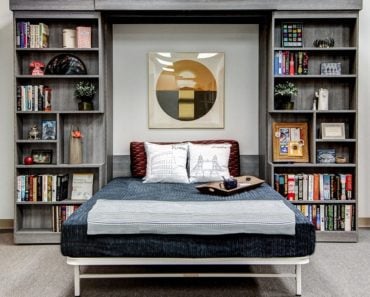 Wall bed set up as bed with bookshelves on both sides.