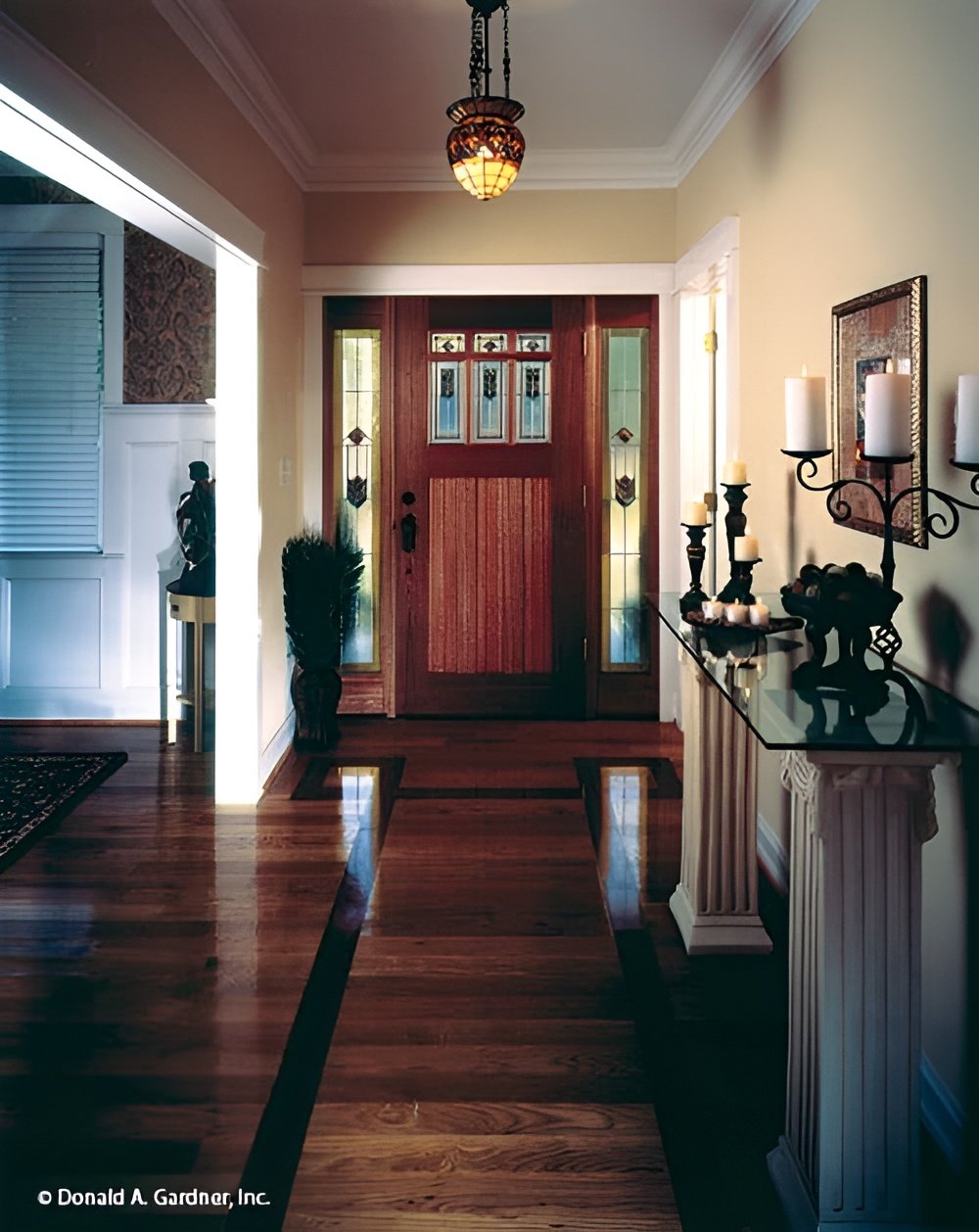The foyer has a wooden front door and a glass-top console table topped with decorative candles.