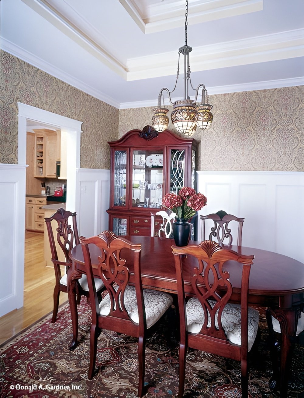 Formal dining room with a step ceiling, wainscoted walls, an oval dining set, and a matching china cabinet.