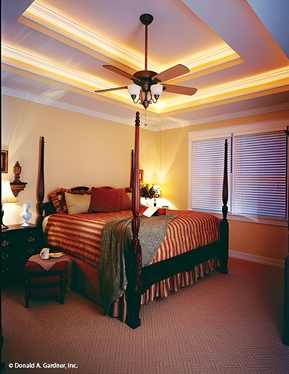 The primary bedroom features a four-poster bed and a stunning step ceiling accentuated with coved lighting.