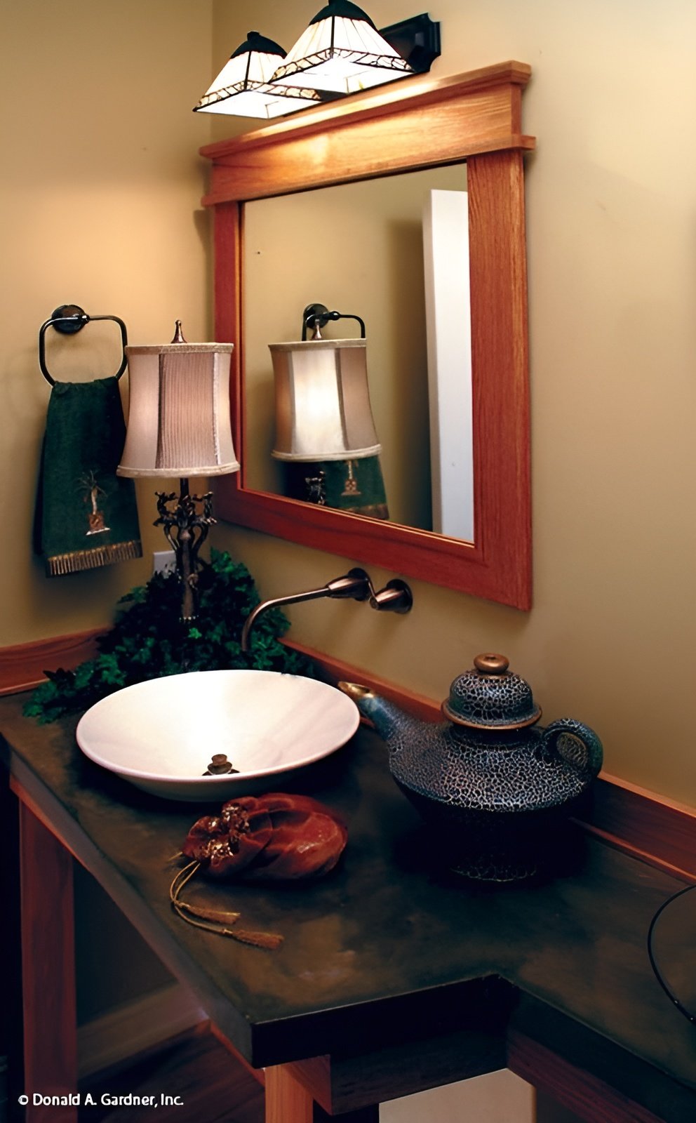 Powder room with a wooden framed mirror and a washstand topped with a vessel sink.