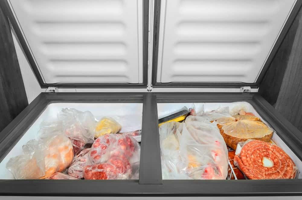 An open freezer full of frozen meat.