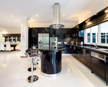 Large l-shaped kitchen with black cabinets and a black island