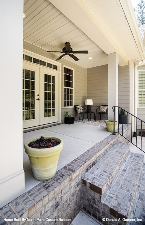 A stone stoop with wrought iron railing complements the covered porch.