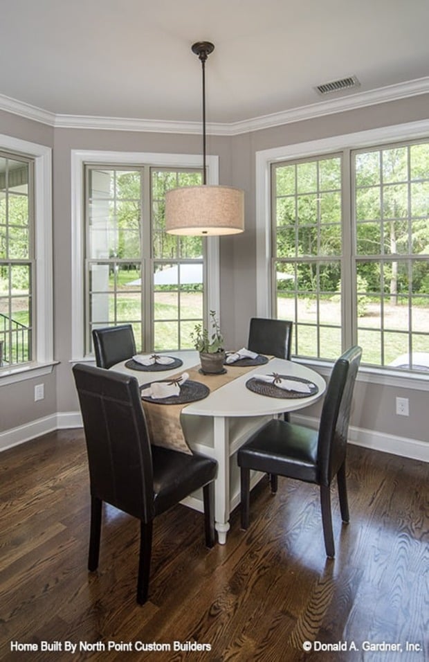 Breakfast nook with a round dining table, black leather chairs, and a drum pendant light.