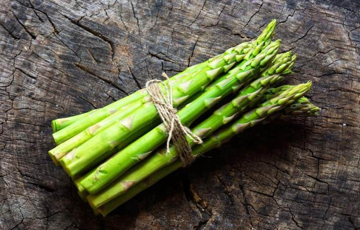 Bunch of asparagus on a wooden log