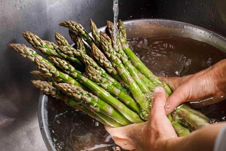 A man washing asparagus with water