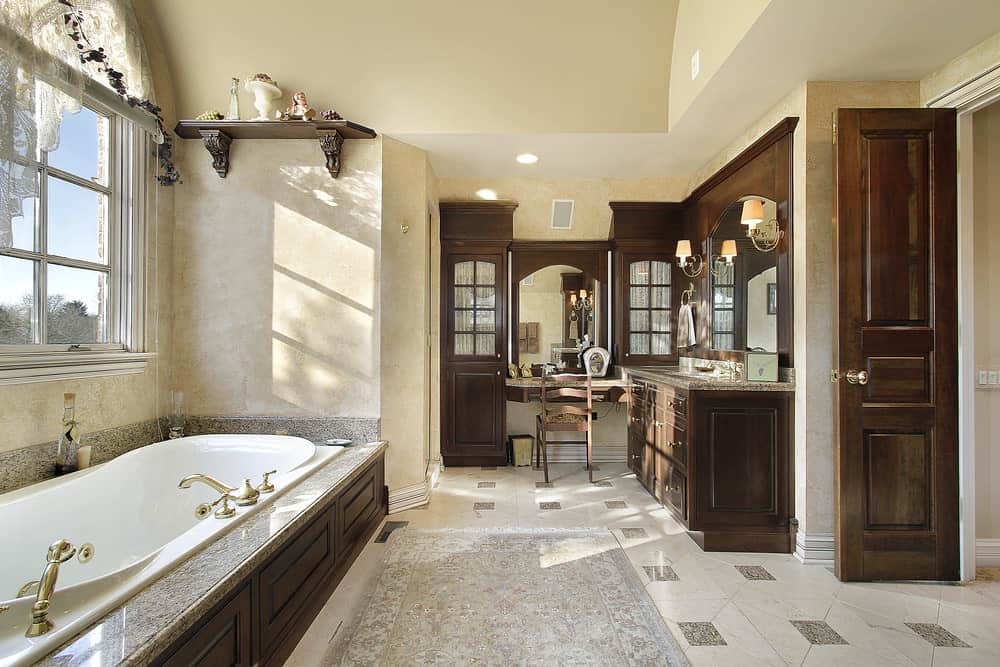 Luxury primary bathroom with tile flooring, vanity, and a drop-in tub with crown molding.