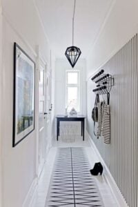 Black and white stripe walls and pattern runner dominate this light and airy foyer. Framed art and a well placed console table, right when you enter, add depth and character to the design.
