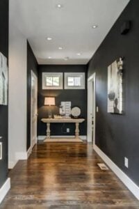 This narrow but stylish foyer has natural wood floors that compliment the black walls and white trim.