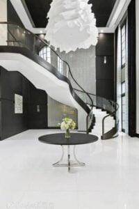 A foyer boasting elegance all over the space. The black walls blend well with the white flooring and ceiling light. The staircase featuring white steps and black railings are absolutely just jaw-dropping.