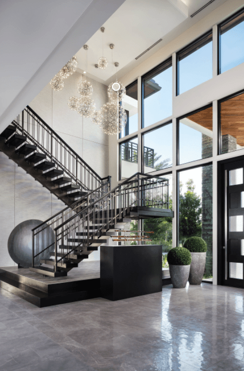 Modern foyer featuring a black floating staircase illuminated by luxurious glass ball chandeliers against the paneled glass walls.