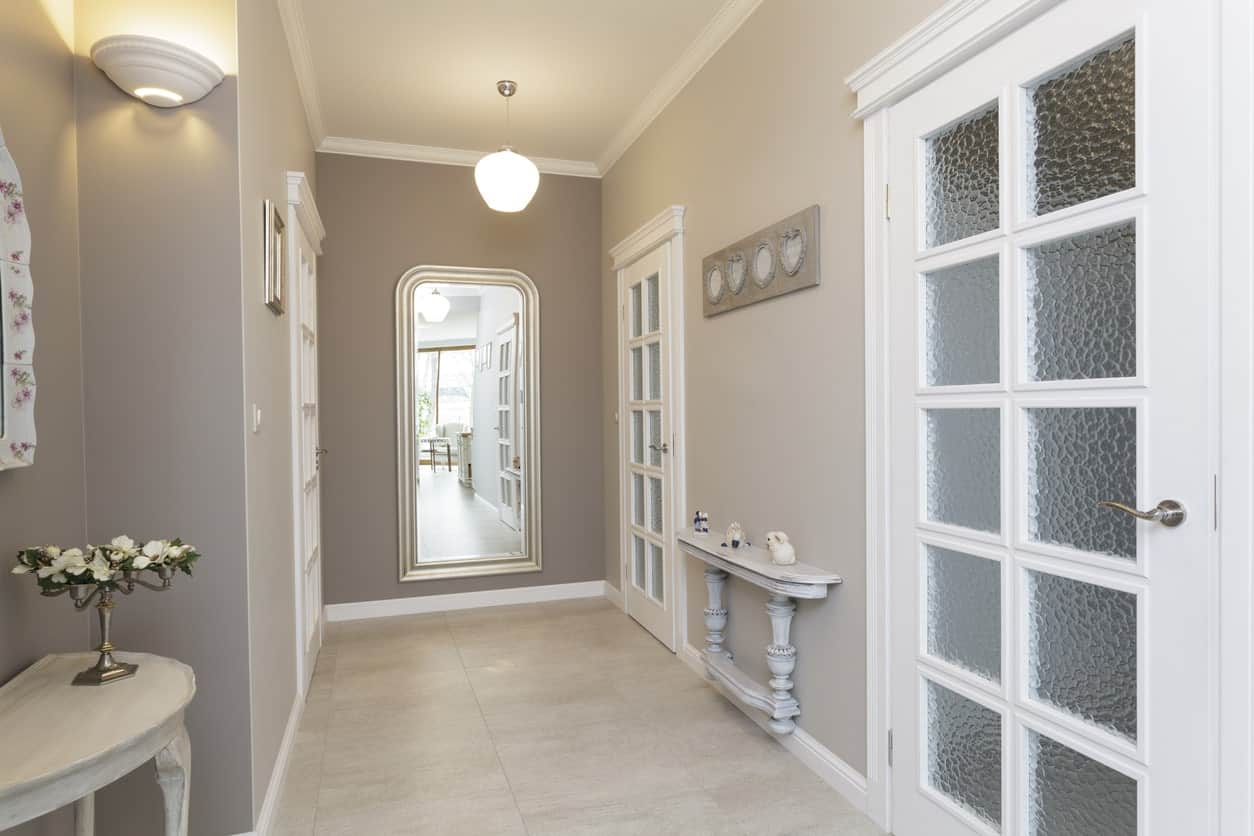 This foyer features tiles flooring surrounded by gray walls. French doors lead to home's specific rooms.