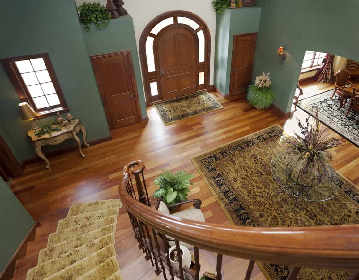 This large foyer boasts a beautiful combination of green and brown colors. The rugs look so elegant.