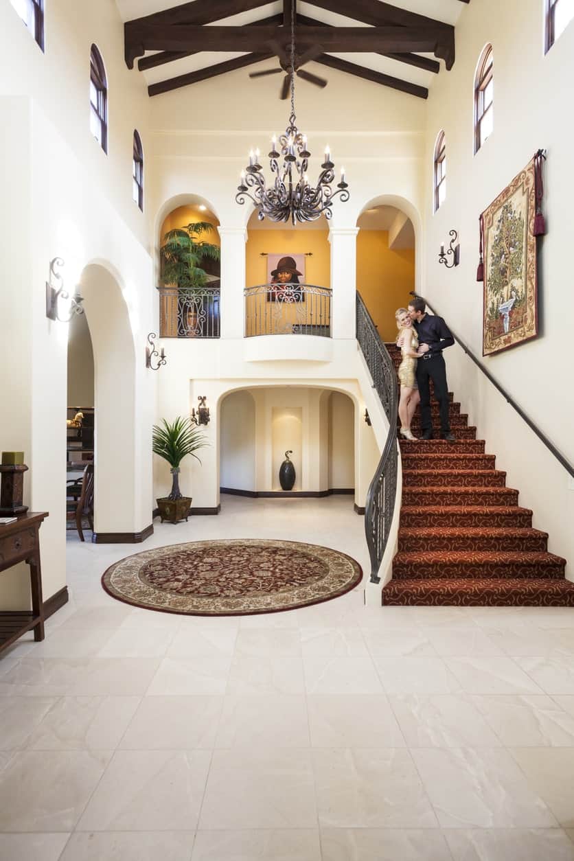 This large foyer looks so magnificent. The tiles flooring fits perfectly well with the rug and staircase's steps. The chandelier set on a stylish ceiling is definitely an eye-catcher.
