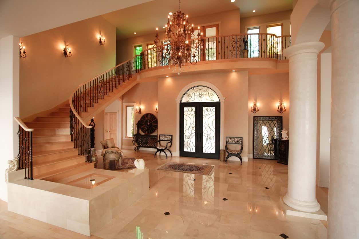 A very elegant large foyer featuring bright lights from the grand chandelier and classy wall lighting. The tiles flooring is sparkling from the brightness.