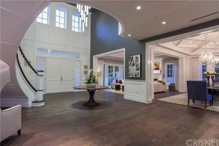Large foyer with hardwood flooring and combination of dark and white walls. The staircase looks magnificent as well.