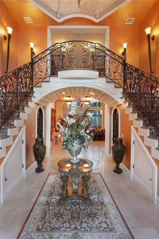 This large foyer boasts an elegant look with its flooring, walls, ceiling, lighting and staircase.