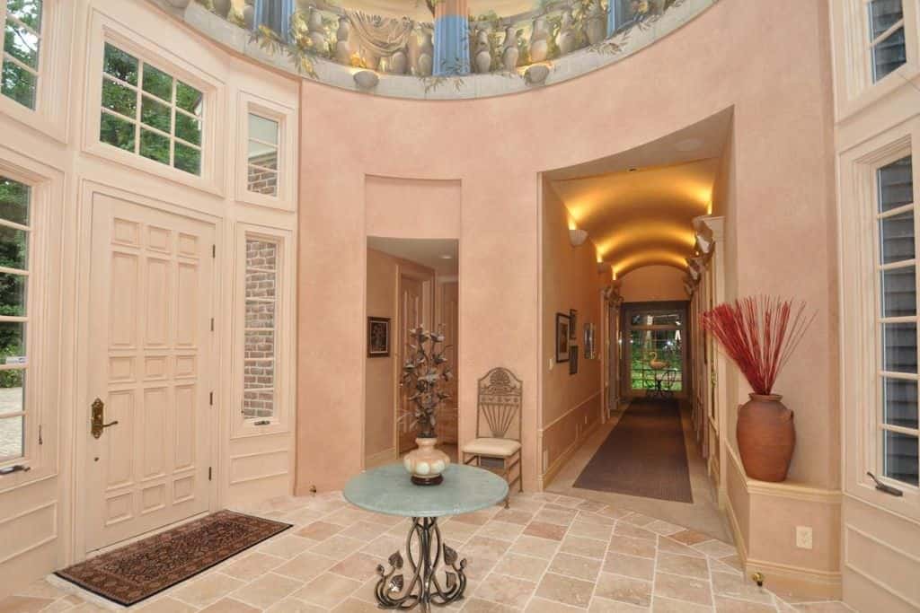 Large bright foyer featuring tiles flooring and a circular main hall. The hallway is lighted by stunning set of wall lighting.