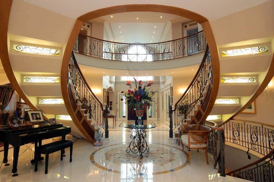 This stylish and elegant foyer features a very charming staircase, flooring and scattered ceiling and wall lighting. The foyer is just jaw-dropping.