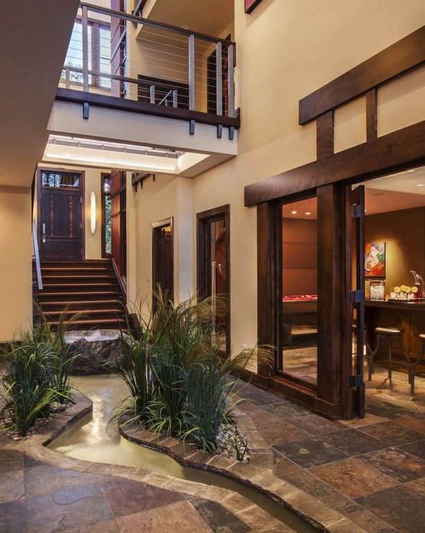 This modish large foyer features a very classy flooring with a tiny river and plants, adding a life to the home.