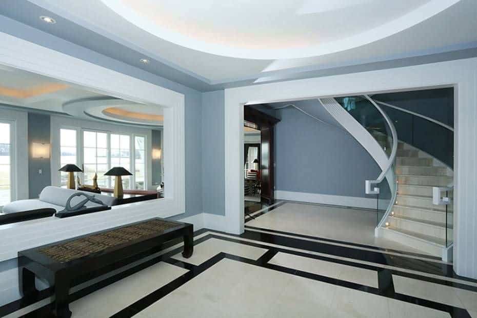 Large modern foyer with gray walls and stylish flooring along with the elegant staircase. The foyer's style looks perfect together with the home's style.