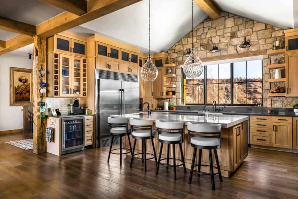 The kitchen is equipped with stainless steel appliances, wooden cabinetry, and a breakfast island lined with round bar stools.