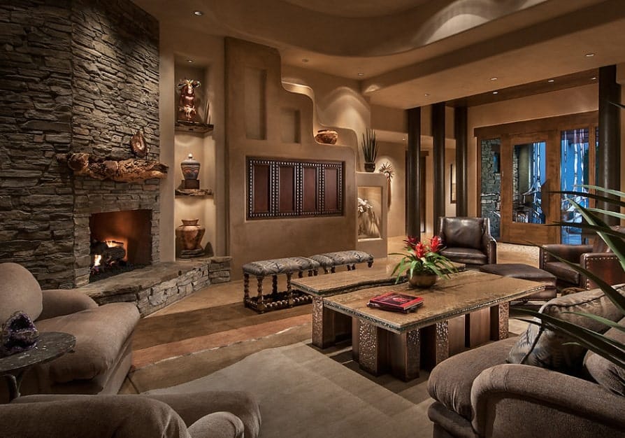 A stunning living room setup featuring classy seats, elegant tables and glamorous decorations. The fireplace is absolutely jaw-dropping.