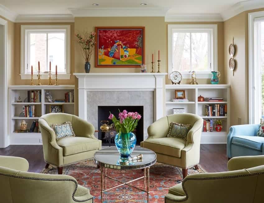This living room offers cozy seats and a lovely rug near the stylish fireplace. There are shelves on both sides of the fireplace.