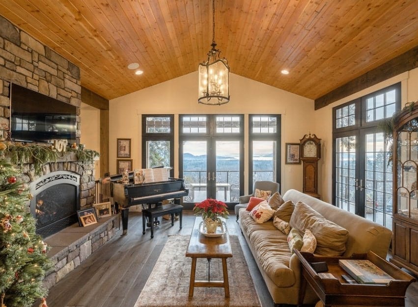 A large living room with a rustic finish on the hardwood flooring, vaulted ceiling and fireplace. The glamorous ceiling lights shower down the brightness to this gorgeous living space.