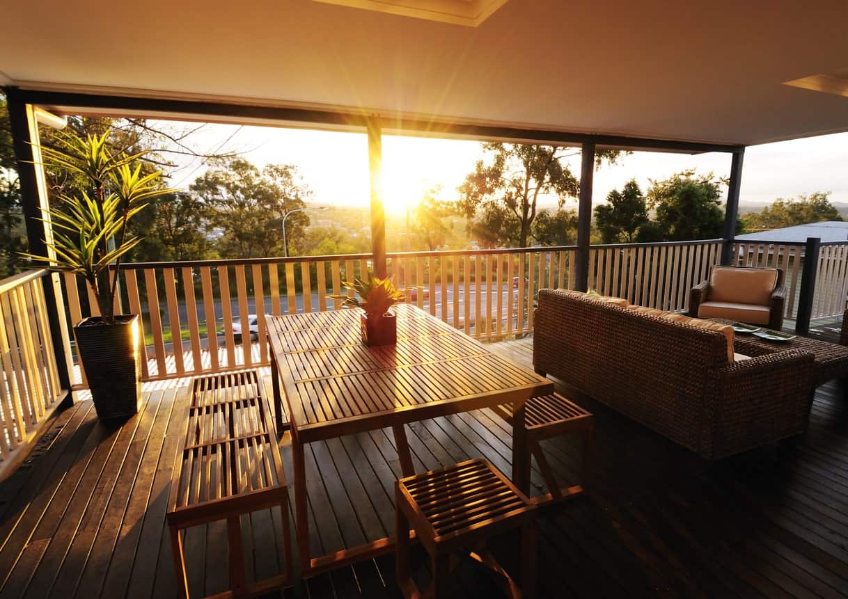 Simple covered deck with a wooden dining table set and rattan sofa set with cushion seats and foam backrests.