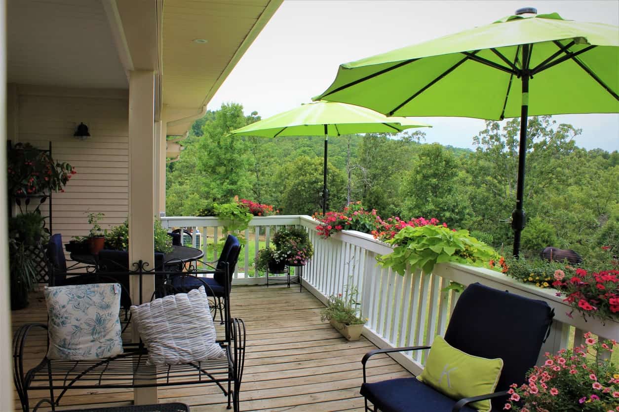 This deck has a small dining table set and lounging seats shaded by a couple of umbrellas.